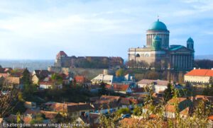 Ein idyllischer Blick auf Esztergom, mit der majestätischen Basilika im Hintergrund, die hoch über der Donau thront. Die sanften Hügel des Pilis-Gebirges erstrecken sich im Hintergrund, während die ruhige Donau die Szene durchzieht. Ein idealer Ort, um das Leben in vollen Zügen zu genießen – sei es beim Arbeiten im Home Office oder bei einem Spaziergang durch die malerische Natur.