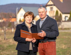 Paar prüft Unterlagen und Checkliste beim Haus kaufen in Ungarn vor einem Wohnhaus als Vorbereitung auf den Immobilienkauf